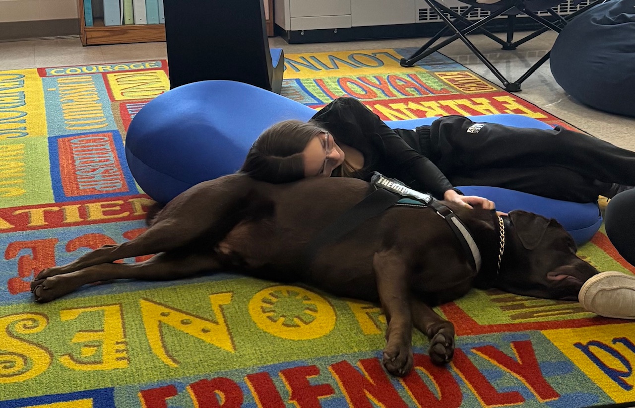 Tucker the therapy dog sitting with Gowanda Elementary students during a reading lesson
